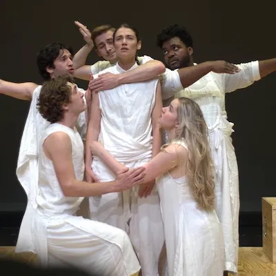 Several people dressed in white surround a young woman, hugging her waist, chest, etc. 