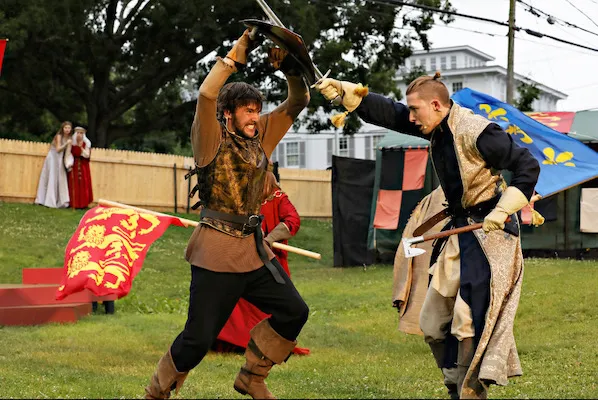 Two men in period clothing engage in a swordfight